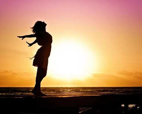 Una donna che si apre per la felicità.Sullo sfondo un cielo luminoso..